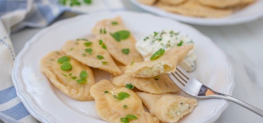Plated pierogi ruskie with sour cream, the most common Polish dumpling filled with potato and twaróg cheese.